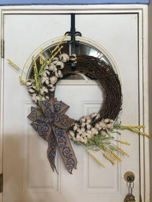 Grapevine wreath with stalks of cotton and yellow flowers.