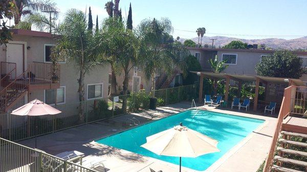 Large sparkling pool with covered patio, picnic tables, umbrellas and loungers