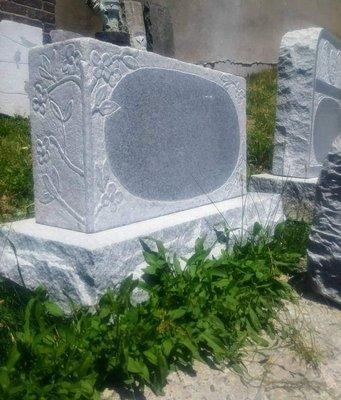 A grey granite monument with corner carvings.