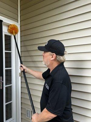 Knocking down spider webs and wasps nest on the exterior of your home