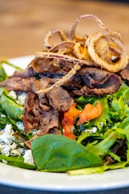 Tri-tip salad, smoked trip tip over chopped greens, bleu cheese crumbles, tomatoes, fried onions, served with balsamic vinaigrette.