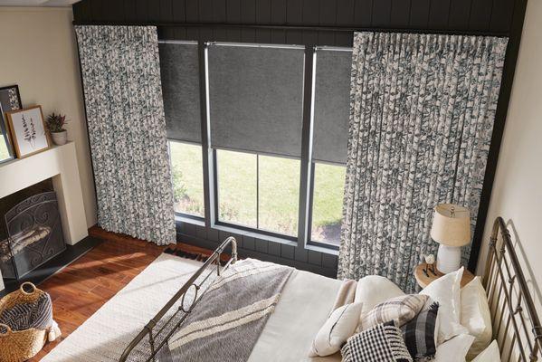 Roller shades layered with custom traversing drapery.