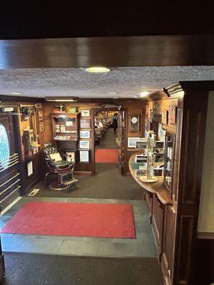 At bottom of stairs , front doors on left and front desk to right of the red rug. Open door in middle is to the restaurant.