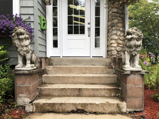 Porch entrance with crumbling concrete stairs and bland cinder block sides.