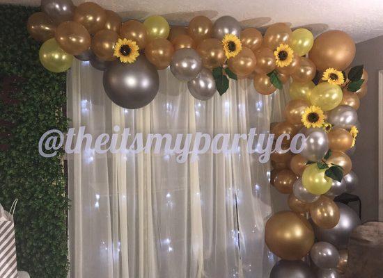 Grass wall, pipe and drapes that have lights and organic balloon garland. The perfect backdrop for your event.