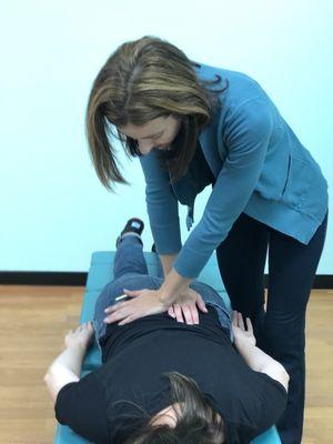 Dr. Julie performing an adjustment with a chiropractic table called a drop table which provides for a gentle adjustment.