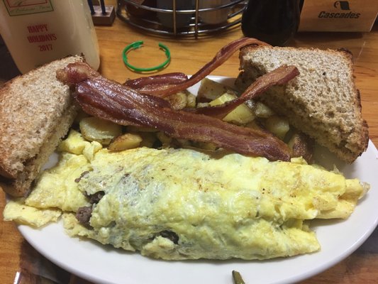 Steak and cheese omelette with peppers and onions. Home fries. Bacon and homemade wheat bread!