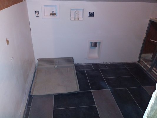 Laundry room rough in complete with ceramic tile and overflow drain.