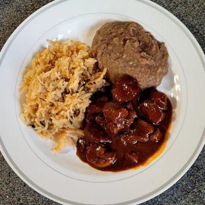 Pork asado served with refried beans and mexican rice.