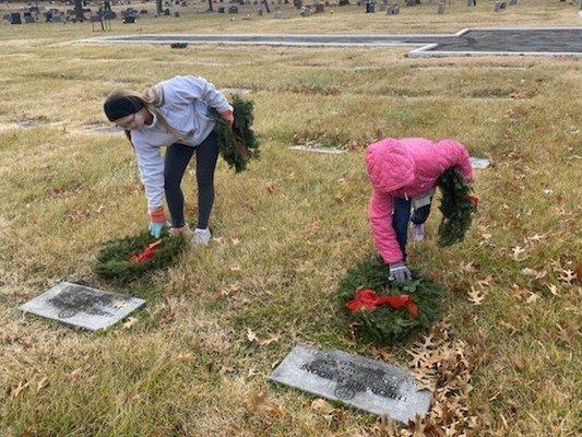 Young girls laying wreaths. 2019