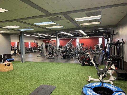 Stretching and multi use turf area and beyond it the free weights machines and benches.