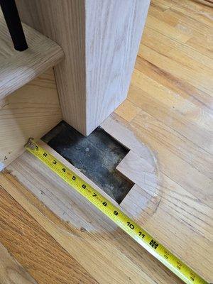 Hole in floor after stair railing company installed new newel, before repair.