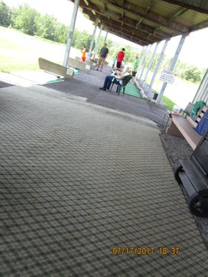 Al and Linwood, and two customers practicing under the covered tees.