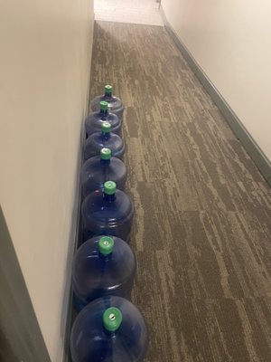 7 empty 5 gallon water jugs that haven't been picked up in 5 months.