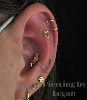 Embrace the eclectic elegance of ear piercings, blending stones and textures for a mesmerizing statement. By Logan