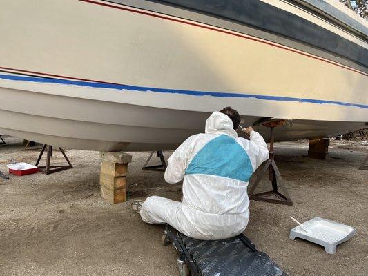 Ken is applying the first coat of primer to the boat.