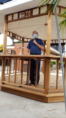 Pastor preaches from the gazebo, several feet away from the congregation.