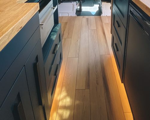 Handcrafted galley-style cabinets with LED toe-kick lighting in our tiny home - a blend of space efficiency and elegance, showcasing Vannish