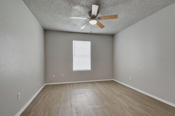 an empty room with wood floors and a ceiling fan