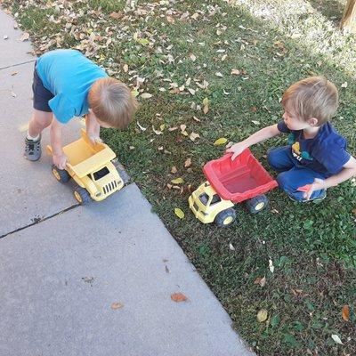 Gross Motor Skills driving dump trucks on the playground with friends.