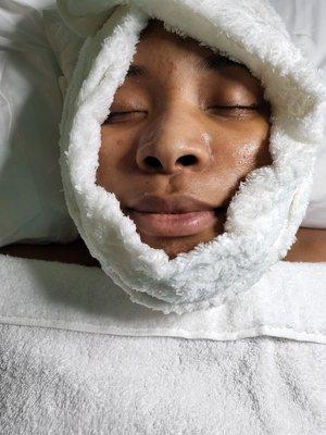 Warm towel-ready to remove exfoliate off of guest face.