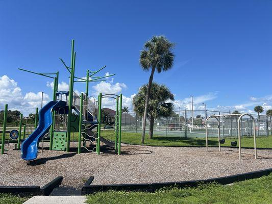 playground and tyke swings. tennis court behind. there is also a sand volleyball court.