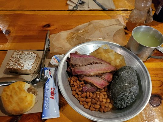 The meal including brisket, baked beans, hot potato, biscuit and applesauce