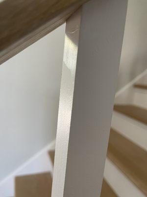 The shiny portion is the primer. He did not paint the posts all the way to the top. He was too lazy to tape the wood railing. Awful!