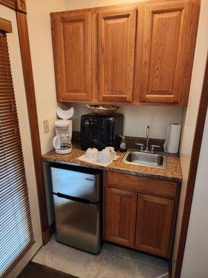 Kitchenette, with refrigerator, microwave, coffee machine and sink.