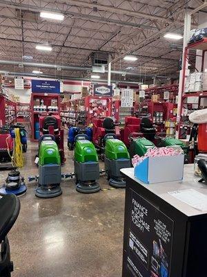 Interior view of floor scrubbers and rows of red shelves with products at Jon-Don