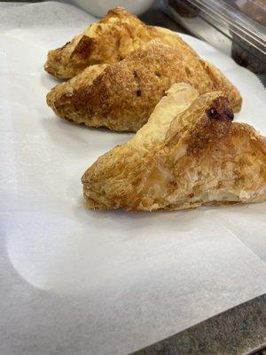 Freshly-baked Apple Turnovers with Apple filling inside the pastry topped with cinnamon and sprinkled with sugar crystals.