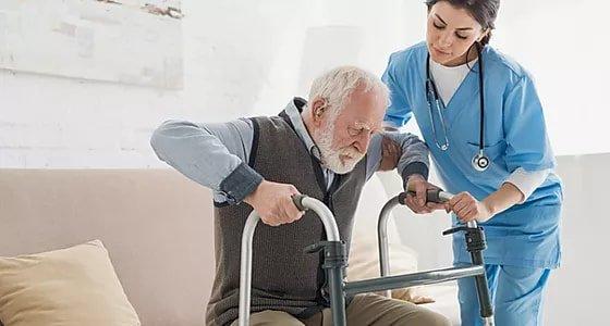 Caregiver providing standby assistance and encouragement to a client attempting to stand up.