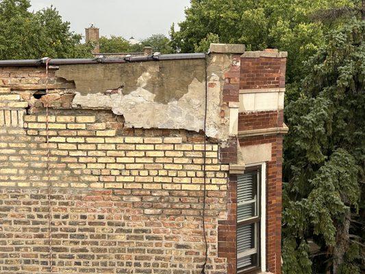 Poorly repaired parapet wall on an old brick building in the City Of Chicago.