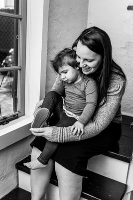 Black and White image of a mother helping her young daughter put on her shoes.