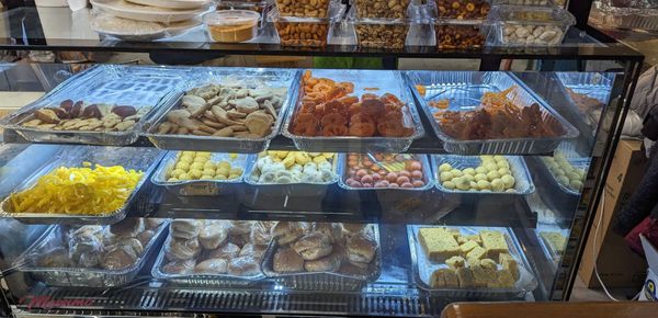 Fresh Snacks and Sweet counter inside the grocery store. fried snacks like samosa, pakkodas are on an adjacent shelf not seen in this pic