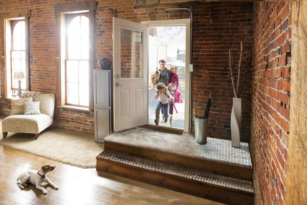 A dog sitting calmly while children enter the home.