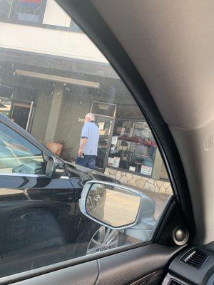 The postmaster shuffling around the parking lot while customers wait in front of a locked post office, during regular business hours.