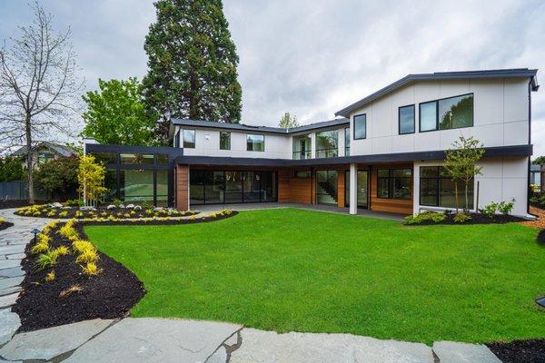 Beautiful, lush yard in custom Vuecrest home. Personalized yard with planter beds, a stone walkway, and a spacious grass lawn.