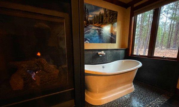 Fireplace and tub overlooking the pines outside our cabin.