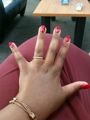 Oval nails, red polish, with gold glitter design along the cuticle and top of nail.