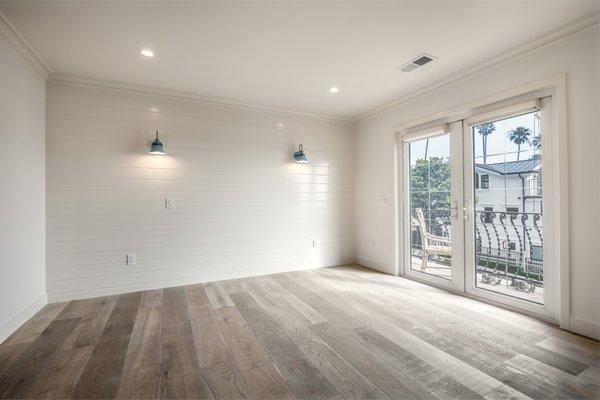 Bedroom featuring new LED recessed lighting, 2 sconce light fixtures, V-groove shiplap accent wall, and new hardwood flooring