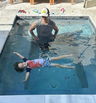 Learning to float on his back in the small pool before shifting to the big pool.