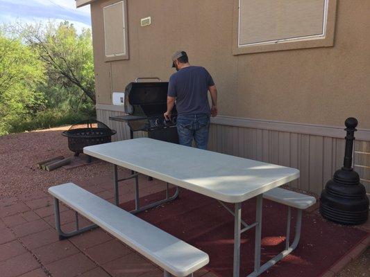 The picnic table by the grill and fire pit, right outside our front door.