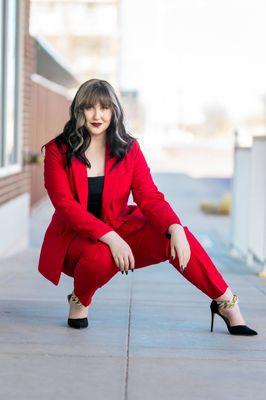 Senior girl wearing a red suit and black shoes posed in downtown Lubbock