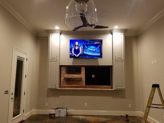 TV Mounted above Full View Glass Wood Door that recesses into the cabinet on the Bar Top