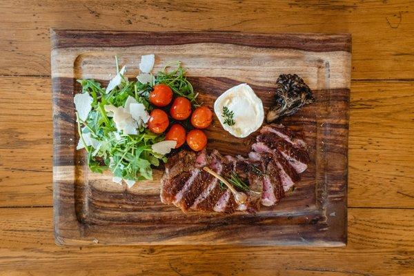 Rib-eye stead with arugula, olive oil and roasted tomatoes.