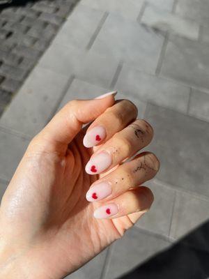 Sheer white dip on natural nails with red hearts done in gel