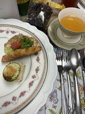 Cucumber sandwich and chicken salad on a croissant. Green tea in cup.