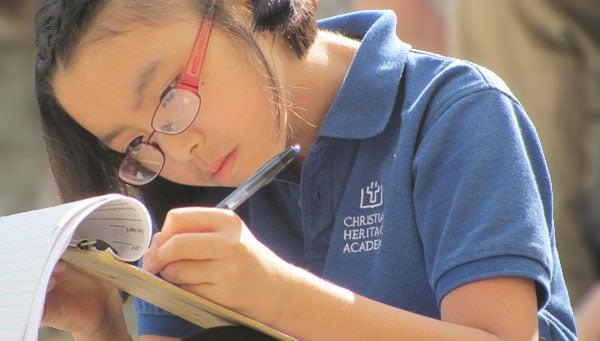 A 5th Grader is writing notes during the field trip to the nature museum.