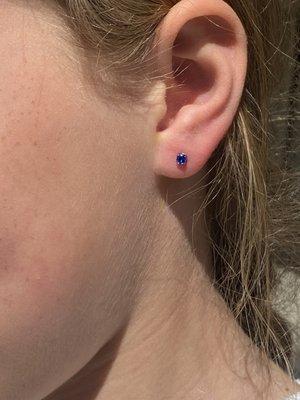 Kid's earlobe piercing with blue prong set gem